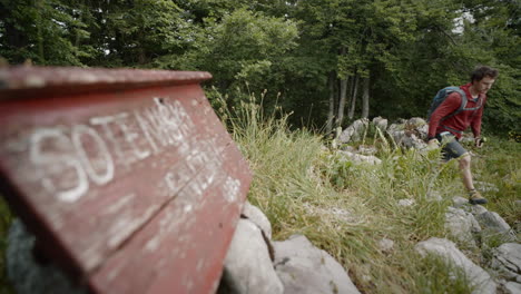 Ein-Junger-Wanderer,-Der-Am-Schild-Vorbeigeht,-Auf-Dem-Soteniški-Snežnik-Steht