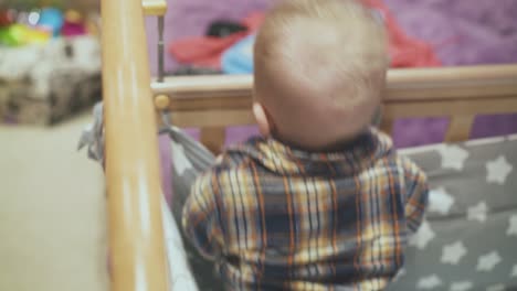 baby plays in rocking soft cot with star blanket in room