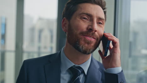 overjoyed boss speaking mobile phone at big windows cabinet closeup. man call