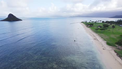 Eine-Ausgedehnte-Luftaufnahme-Der-Ruhigen-Küste-Von-Oahu-Mit-Klarem-Blauen-Wasser,-üppigem-Grün-Und-Der-Ikonischen-Insel-Mokoli&#39;i-In-Der-Ferne