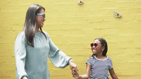 Biracial-mother-and-daughter-dance-against-yellow-background