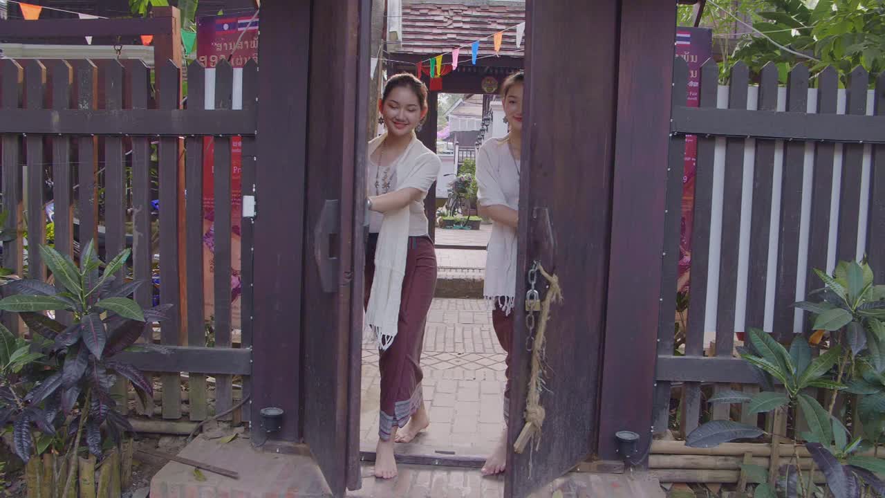 Women in Traditional Thai/Lao Clothing at a Wooden Gate