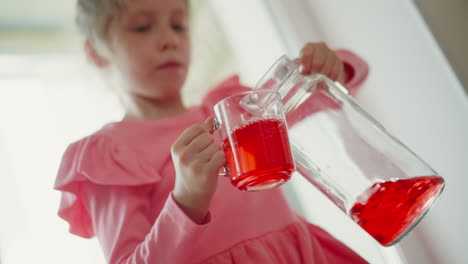 girl pouring red drink into a glass cup