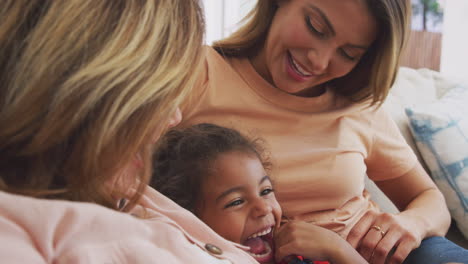 multi-generation female hispanic family relaxing on sofa at home