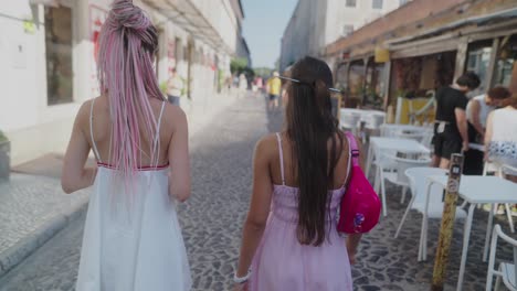 two women walking down a cobblestone street