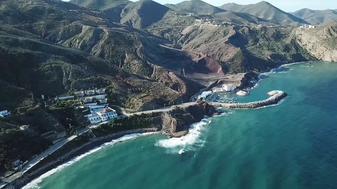 Vertical top-down drone shot showing the dramatic contrast where the rugged Rif Mountains drop directly into the deep blue Mediterranean Sea