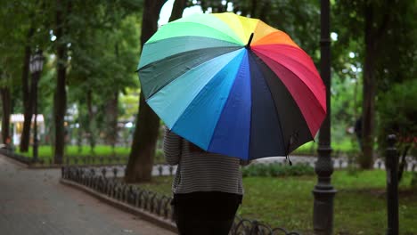 Rückansicht-Einer-Nicht-Wiederzuerkennenden-Frau,-Die-An-Einem-Regnerischen-Tag-Mit-Buntem-Regenschirm-Im-Stadtpark-Spaziert