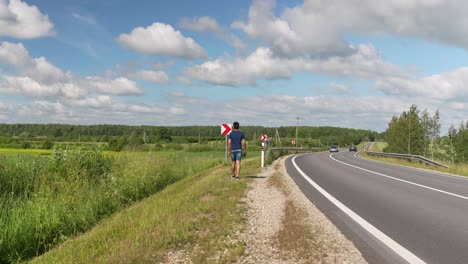 lonely traveler walks beside highway in europe, sunny summer day