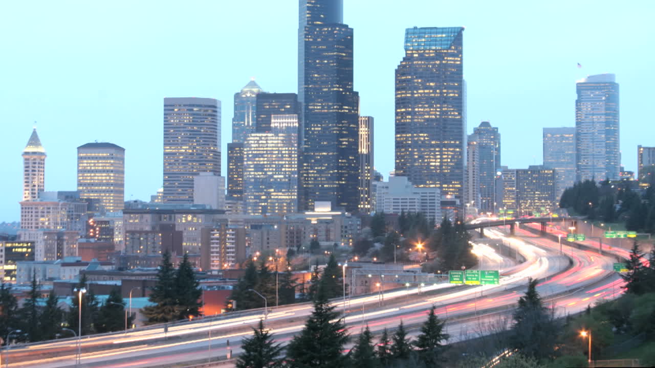 a medida que la hora dorada se oscurece en la noche, el tráfico acelerado se desdibuja en rayos de luz ante un horizonte de seattle iluminado 1