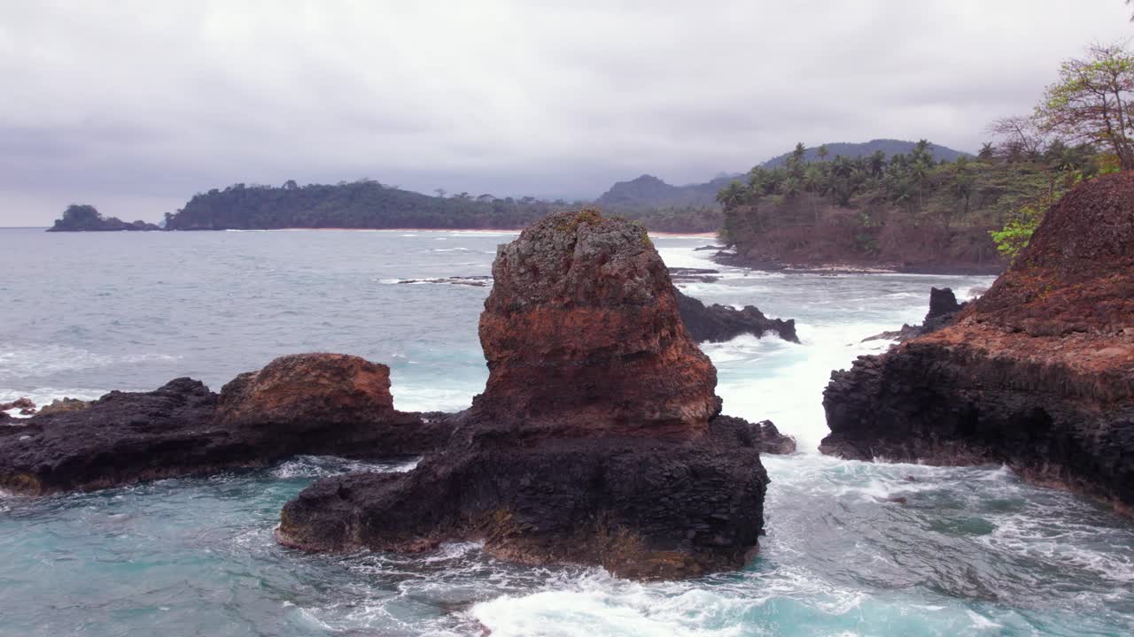 Stormy waves crash on Praia Piscina, São Tomé, a dramatic blend of wild ocean power and serene tropical beach landscape
