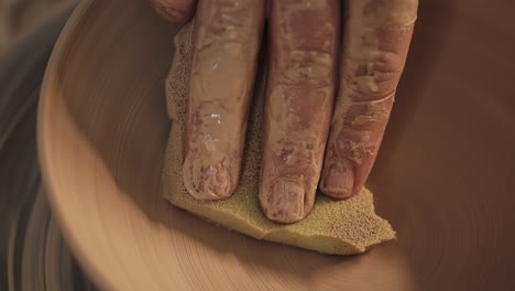 hand smoothing clay bowl on pottery wheel
