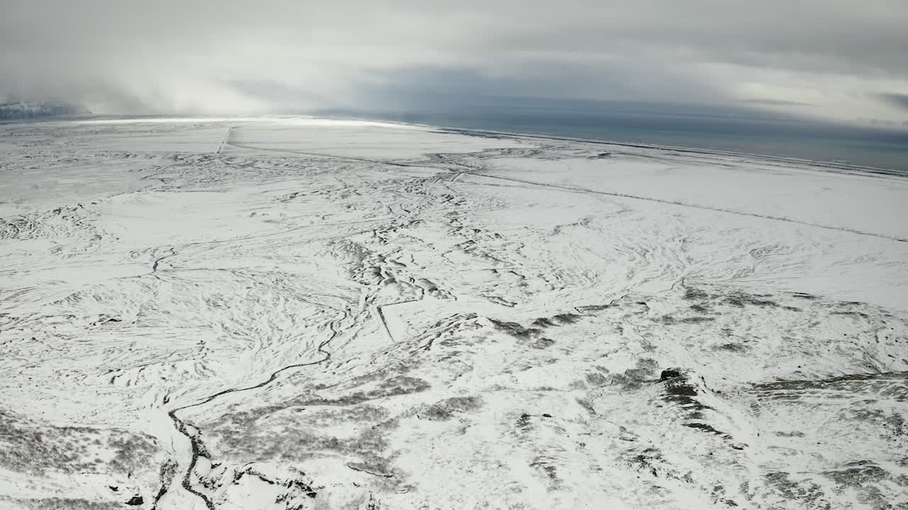Birds eye view over snowy frozen landscape towards coastline in south Iceland.