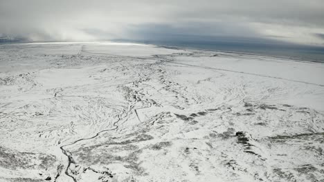 birds eye view over snowy frozen landscape towards coastline in south iceland.