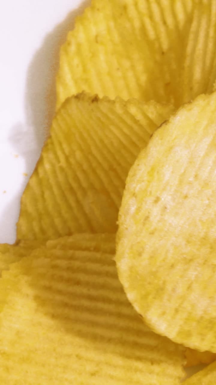 Crisps falling in slow motion with small pieces breaking away. Perfect for food documentaries about unhealthy eating. Vertical video 9:16 format. Ideal for social media reels