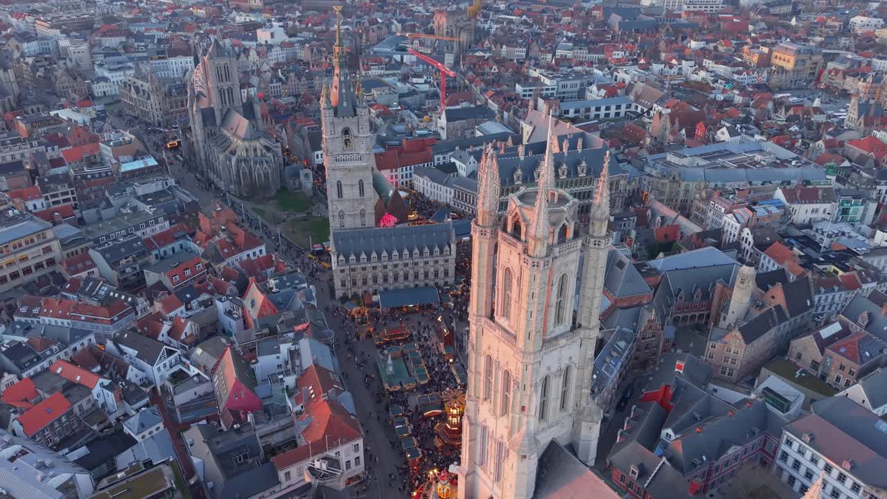 Filmato drone della piazza natalizia di fronte alla Cattedrale di San Bavone a Gand, che rivela gradualmente il paesaggio urbano illuminato con decorazioni festive e architettura medievale