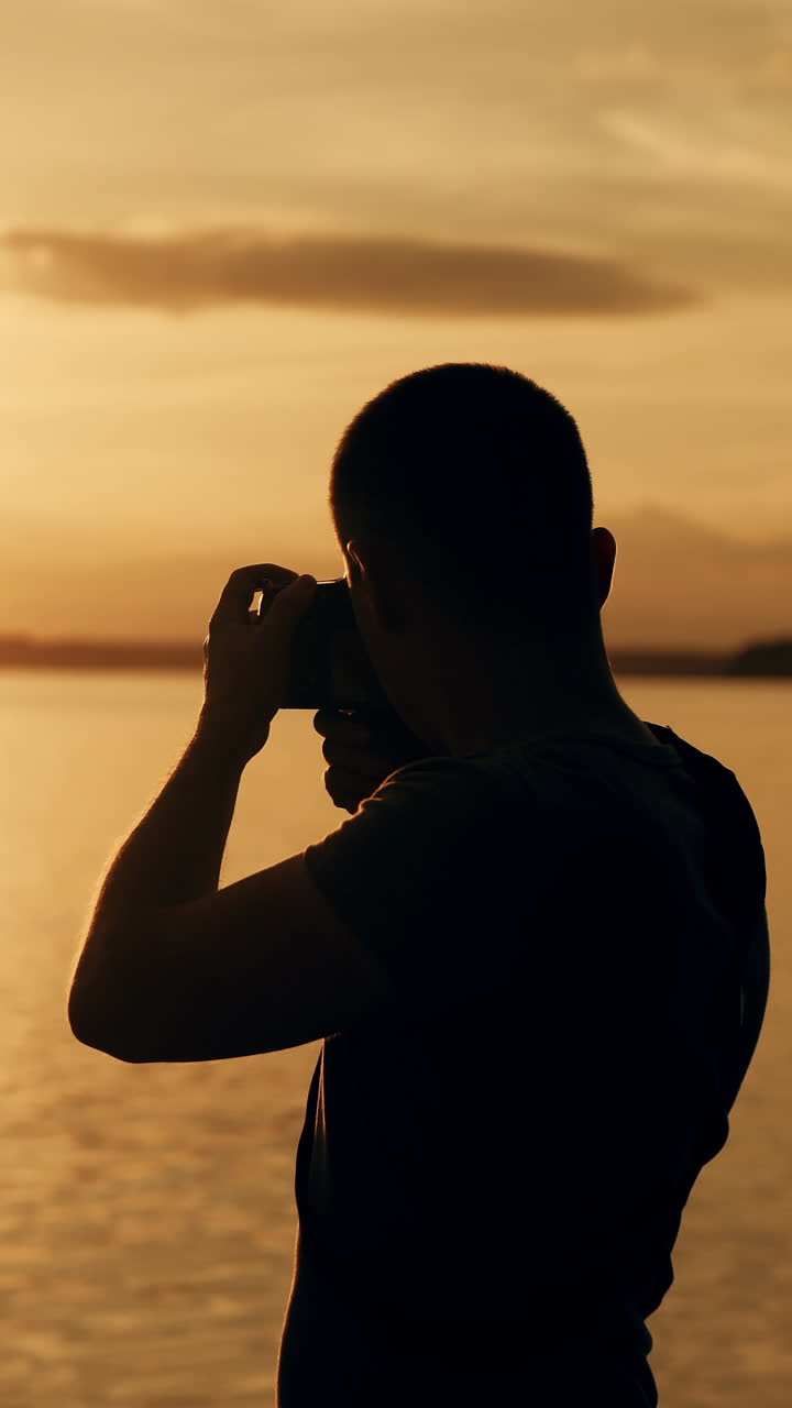 Silhouette of photographer taking photos in the river at sunset time.. Vertical video