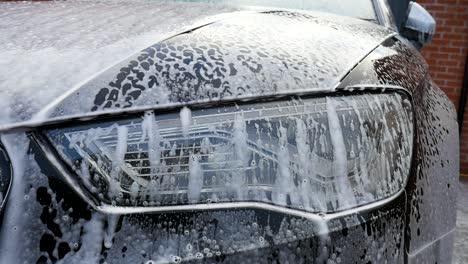 car headlight soaking in shampoo and bubbles