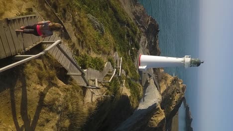 a slim attractive blonde jogs down wooden stairs towards cape egmont lighthouse in the morning