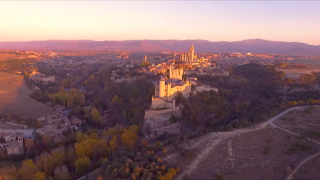 aerial view of segovia alcazar and city during fall with beautiful tree colors and sunset