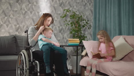 little girl reads while mom holding toddler in wheelchair