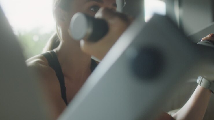 Woman Training with Preacher Curl Machine in Gym