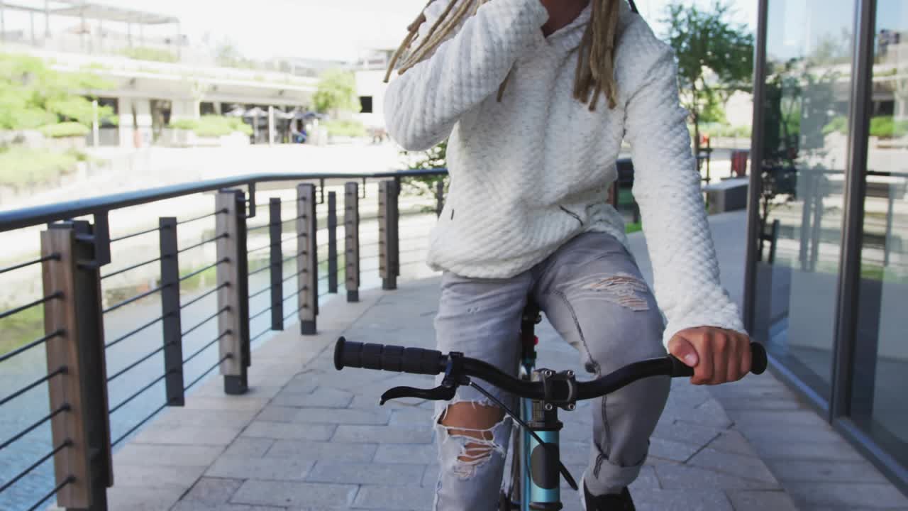 Adult male riding bike waterfront, on phone taking call, social media angry emojis filling frame