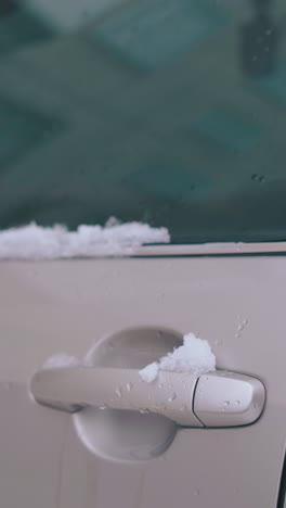 camera motion along closed grey car door with folded rearview mirror and thick snow layer extreme close view