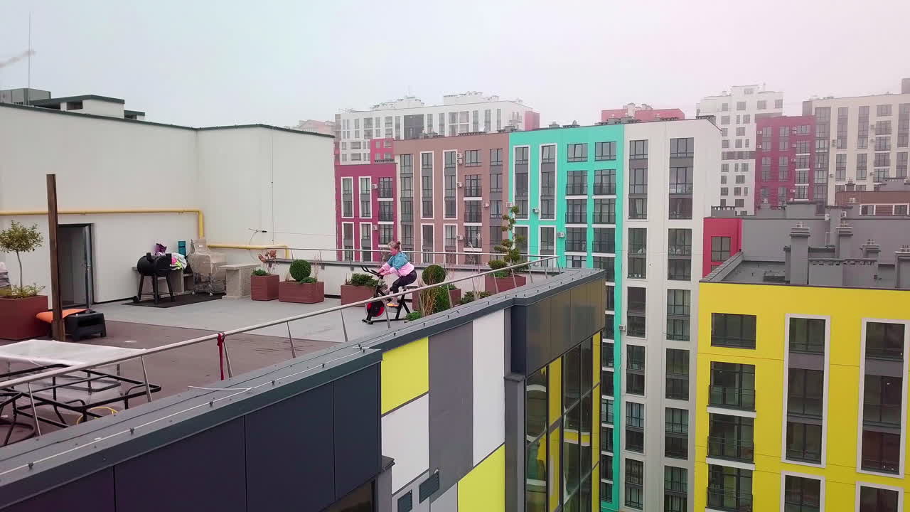 mujer atlética montando en una bicicleta estacionaria giratoria rutina de entrenamiento en el techo de la casa, pérdida de peso