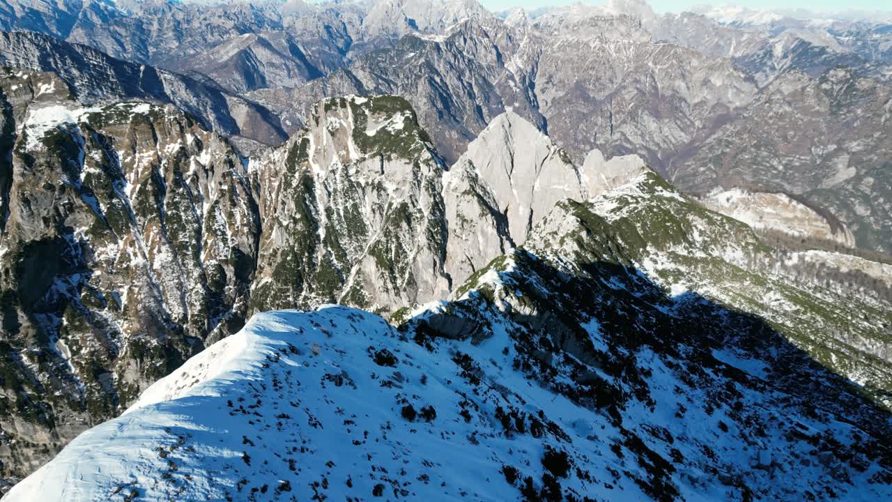 Filmato aereo con drone sopra Monte Raut, Italia: limpida giornata di dicembre con creste illuminate dal sole e pendii innevati in ombra. Ideale per filmato video in stock naturalistico invernale, alpino e cinematografico.