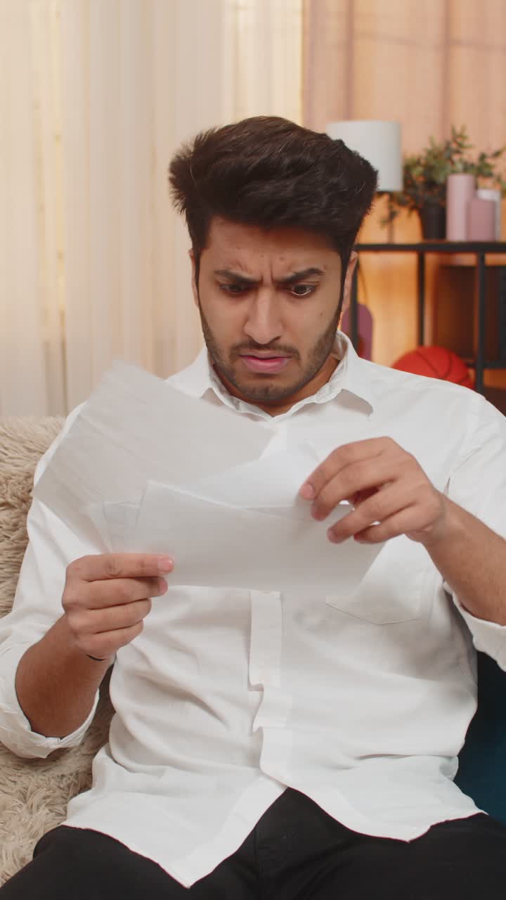 Indian young man shocked nervously checking and throwing bills financial stress debt report mistakes
