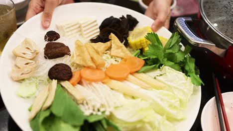 hands arranging ingredients for a hotpot meal