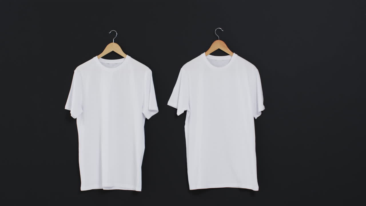 video de dos camisetas blancas en perchas y espacio de copia en fondo negro