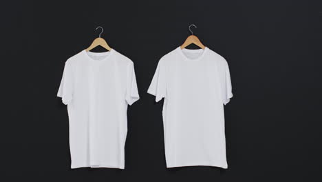 video de dos camisetas blancas en perchas y espacio de copia en fondo negro