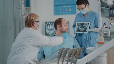 dentist and nurse showing x ray results to patient with toothache