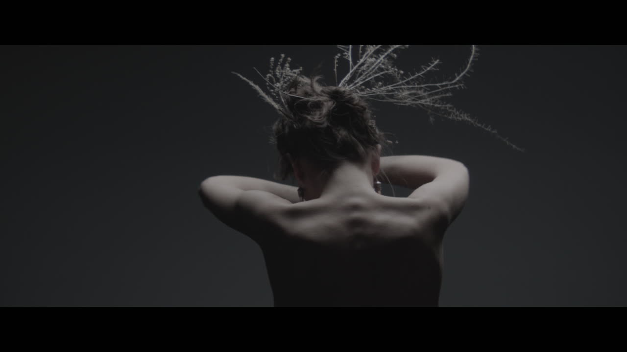 A woman dressed as mother nature moves slowly in a dance-like motion