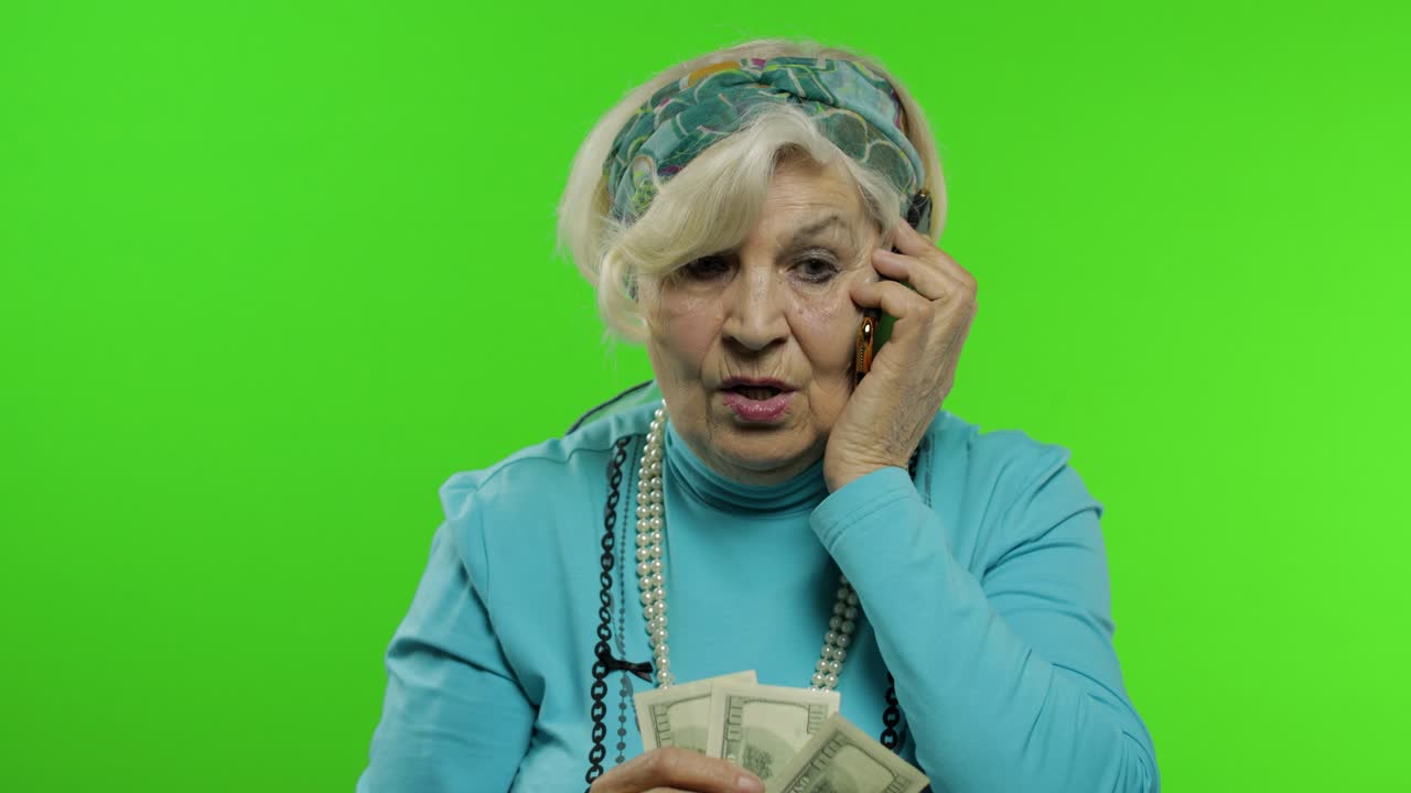 노인 백인 할머니 돈 지폐와 함께 휴대 전화로 이야기
