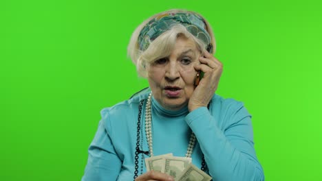 elderly caucasian grandmother woman with money banknotes talking on mobile phone