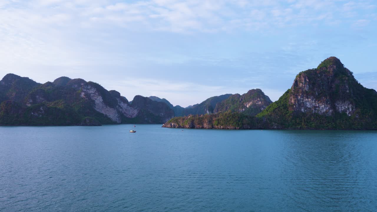 A mesmerizing aerial view of Ha Long Bay's emerald waters embracing limestone karsts and islets that rise dramatically from the sea, creating a mystical seascape with a lone boat