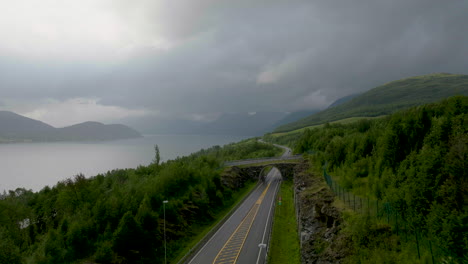 nordkjosbotn-tromso e8 highway crossing verdant norwegian landscape along fjord on cloudy day, northern norway in scandinavia