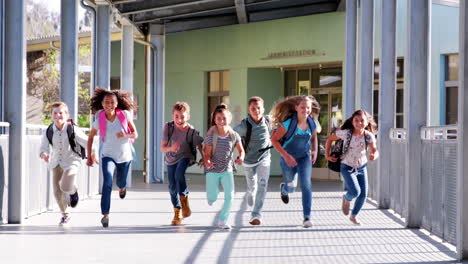 Niños-De-Escuela-Primaria-Corriendo-Hacia-La-Cámara-En-El-Pasillo-De-La-Escuela