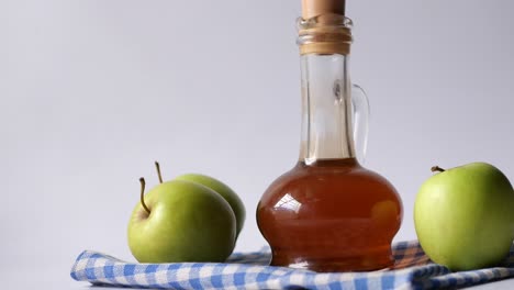 Apple-vinegar-in-glass-bottle-with-fresh-green-apple-on-table-,