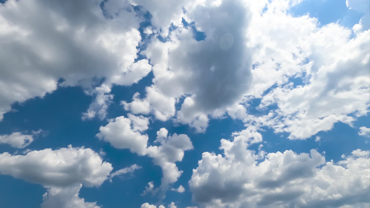 Multiple cotton clouds quickly transforming in the atmosphere. Soft cloudscape formation on sunny daytime. Timelapse.