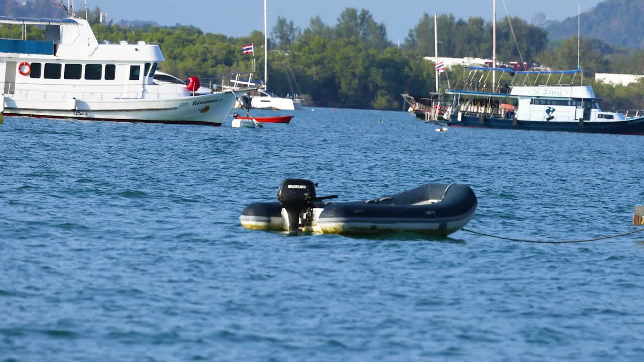 태국 푸켓 근처의 바다에서 부풀어오르는 보트가 부드럽게 떠다니고 있습니다. 이 장면은 은 낮빛 아래 조용한 물과 멀리 있는 보트를 포착합니다.