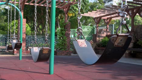 a row of empty swings on a children's playground at a park in hong kong