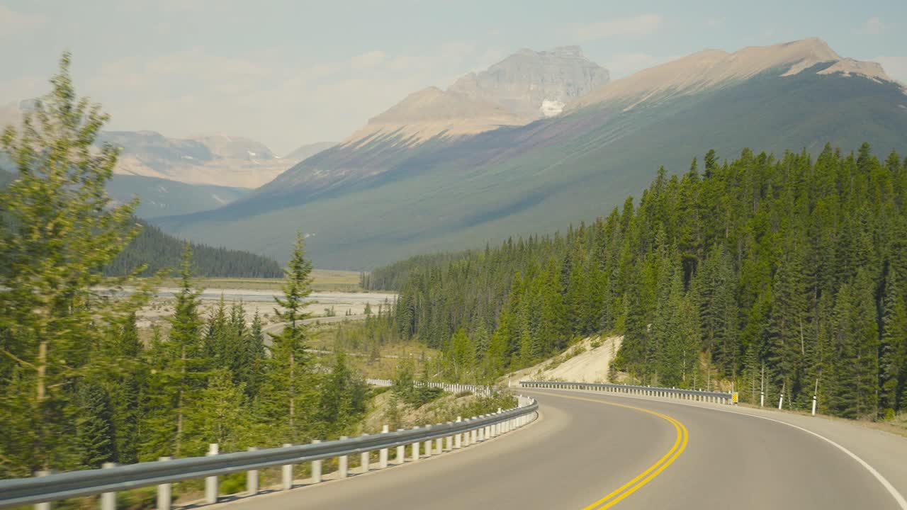 Un road trip panoramico sulle Montagne Rocciose, viaggiando nel Canada durante le ore mattutine, con vista su enormi montagne e sullo splendido paesaggio