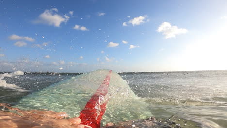 pov, surfer paddling surfboard over ocean wave