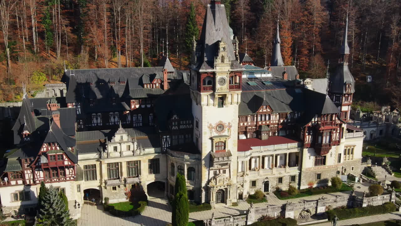 Aerial drone view of The Peles Castle in Romania. Castle with gardens in Carpathians, forest around it, tourists