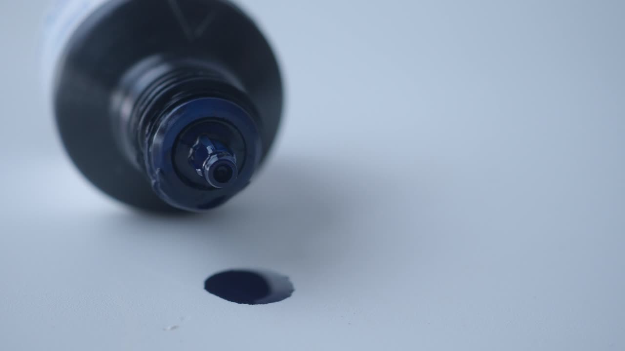 Close-up tetesan tinta biru dari pulpen hitam