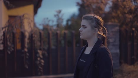 girl with a pigtail walks behind the darkness on a street lit with lamps