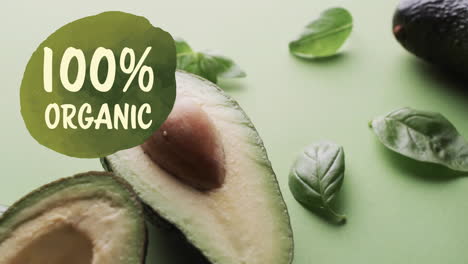 animation of 100 percent organic text over halved avocado on green background